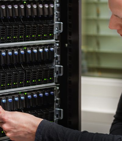 Closeup of mid adult male IT technician analyzing SAN at datacenter